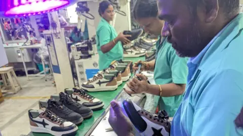Comet Workers inspect shoes at a Comet factory