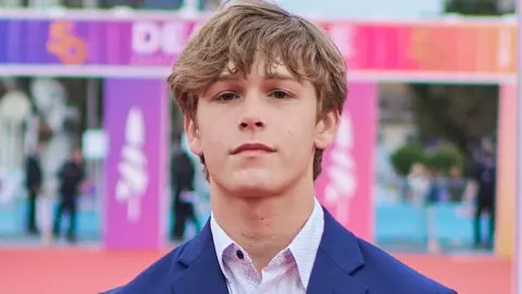Getty Images Hudson Meek in a shirt and jacket looks at the camera on a red carpet at a film festival